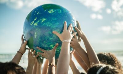 Kids putting their hands on a globe of the earth