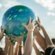 Kids putting their hands on a globe of the earth