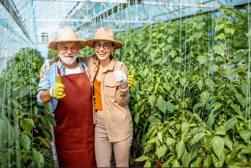 Ecstatic farmer and his daughter giving warming smiles in lush greenhouse 