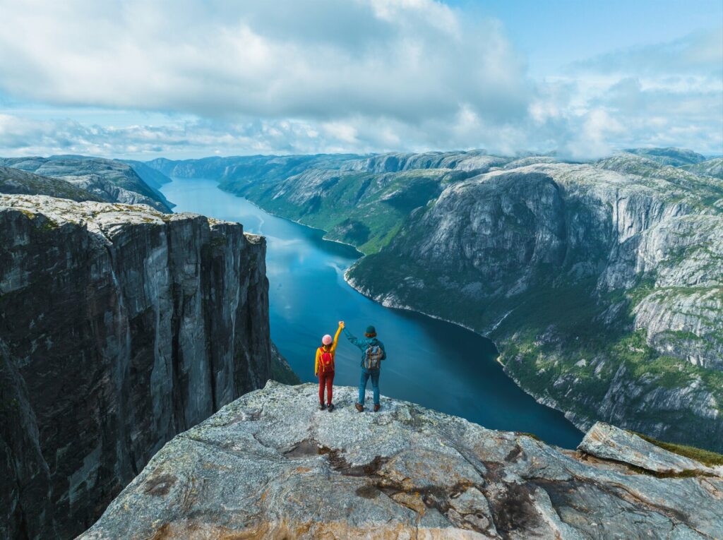 Aerial view of man and woman raising holding arms in mountains in Norway