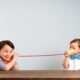 Two children using paper cups and a string to play the telephone game
