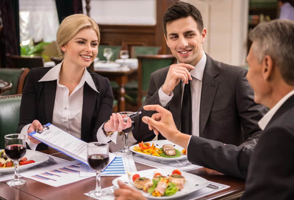 What Skills do You Need To Master to Become an Entrepreneur concept: a group of entrepreneurs listening to their mentor over fancy dinner